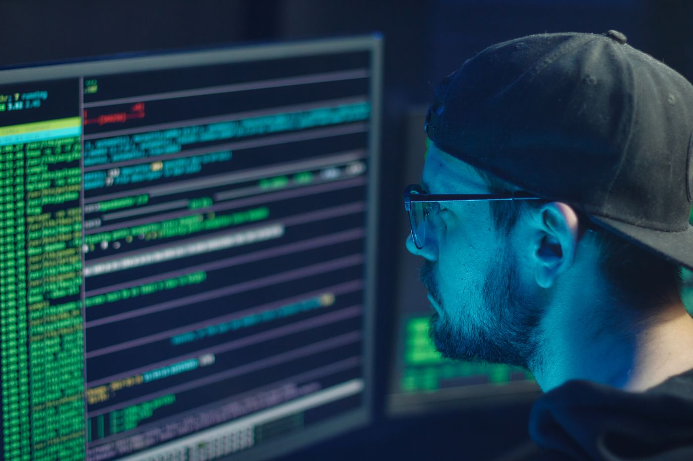 Specialist inspecting lines of code across monitors