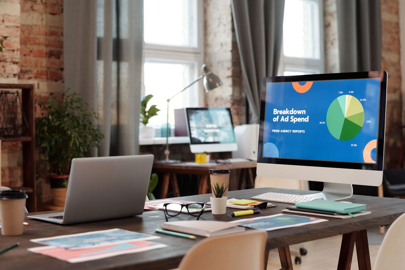Office desk with a campaign spend breakdown on screen