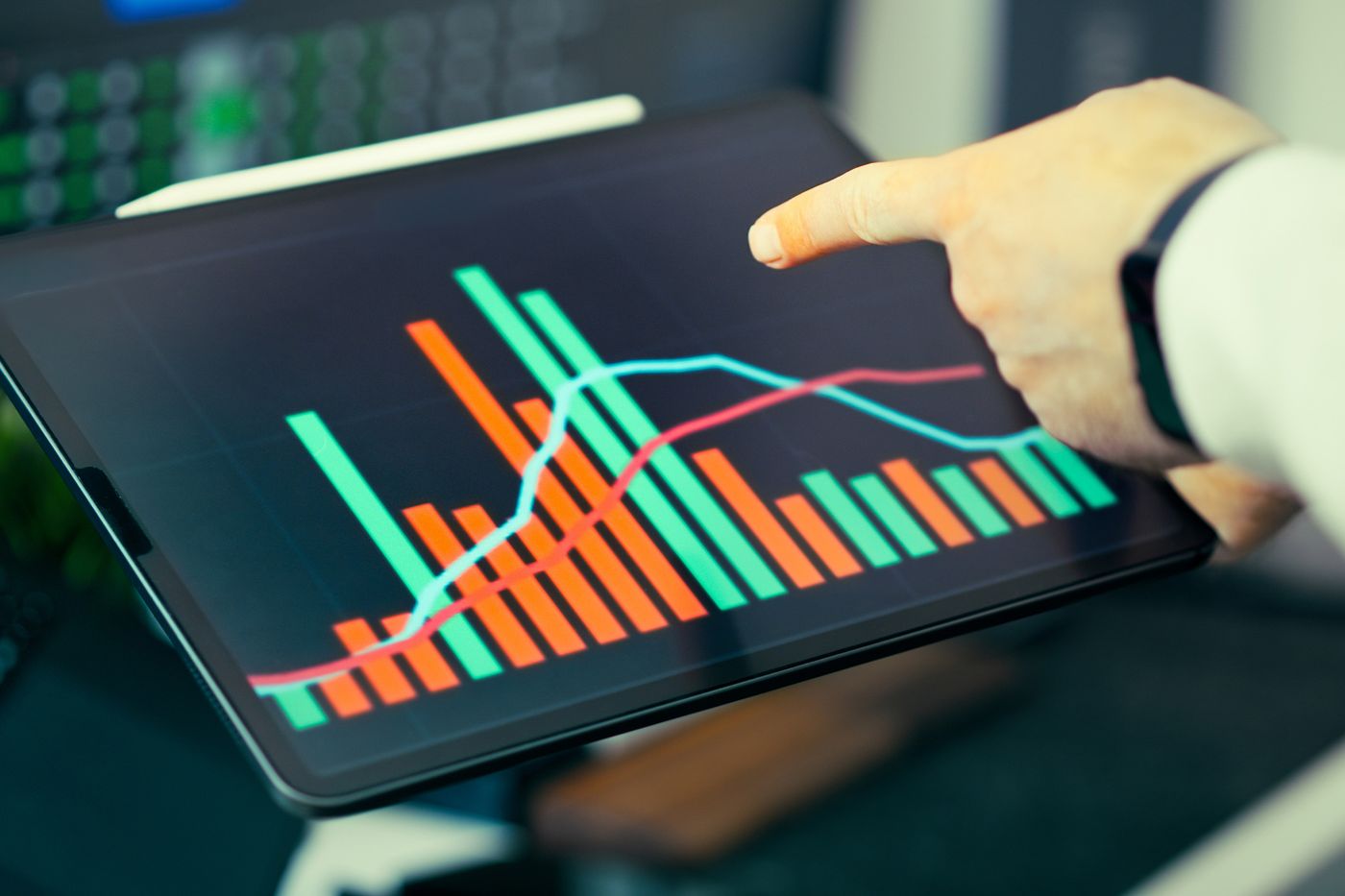 Hand pointing at a live bar and line chart on a tablet